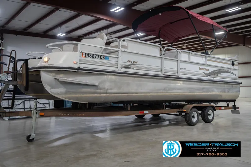 Slide: The Image of 1999 Landau DX24 pontoon boat on trailer in indoor storage facility. - 4