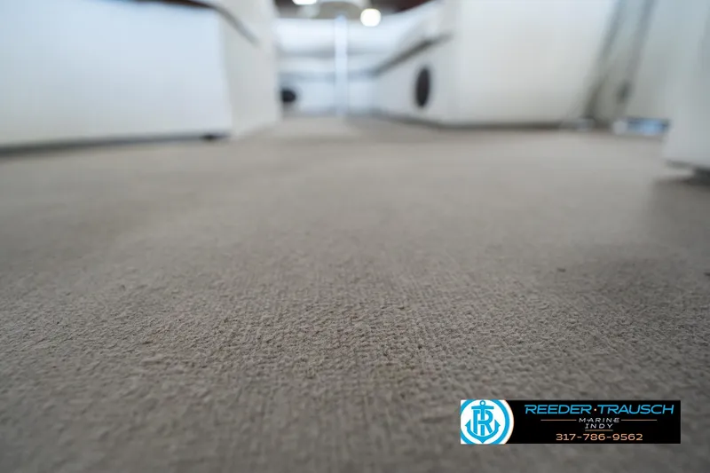 Slide: The Image of Carpeted deck of a 1999 Landau DX24 boat, featuring Reeder-Trausch Marine logo. - 49
