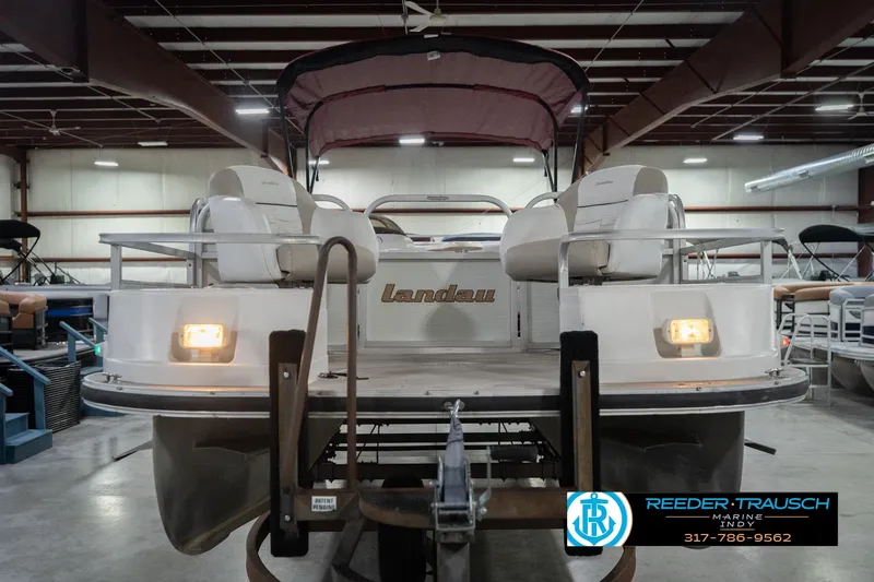 Slide: The Image of 1999 Landau DX24 pontoon boat in indoor storage, featuring cushioned seating and visible lighting. - 5