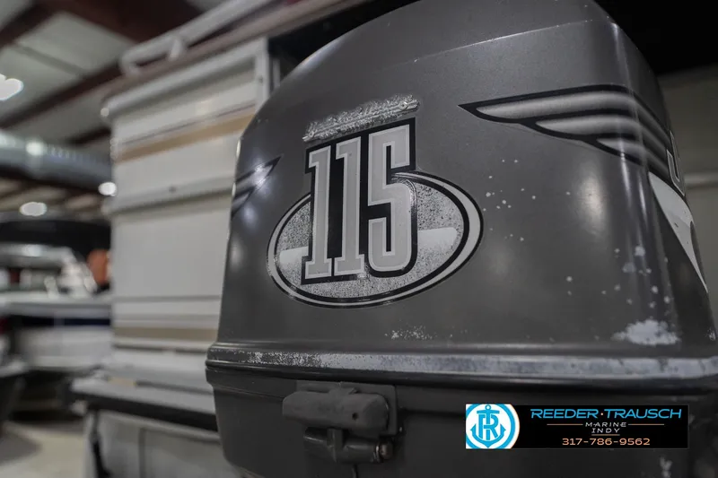 Slide: The Image of Outboard motor with "115" decal on a 1999 Landau DX24 boat in a showroom. - 52