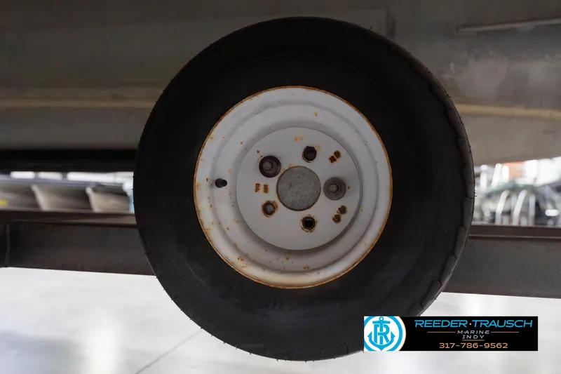 Slide: The Image of 1999 Landau DX24 trailer wheel with visible rust spots in a garage setting. - 57