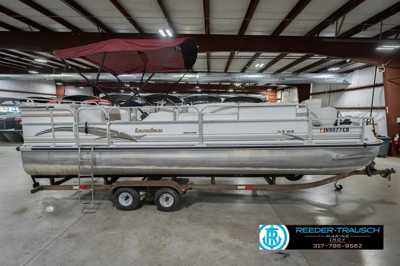 Slide: The Image of 1999 Landau DX24 pontoon boat with red canopy in indoor storage on trailer. - 7