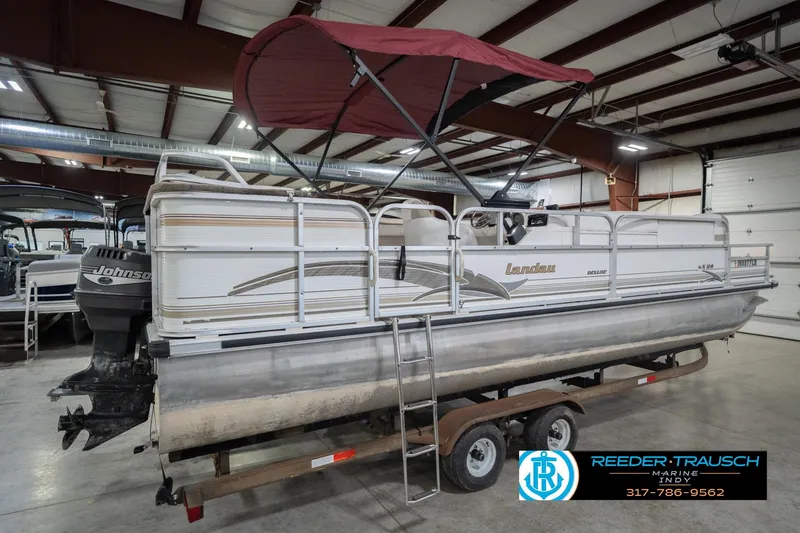 Slide: The Image of 1999 Landau DX24 pontoon boat with canopy in indoor storage on trailer. - 8