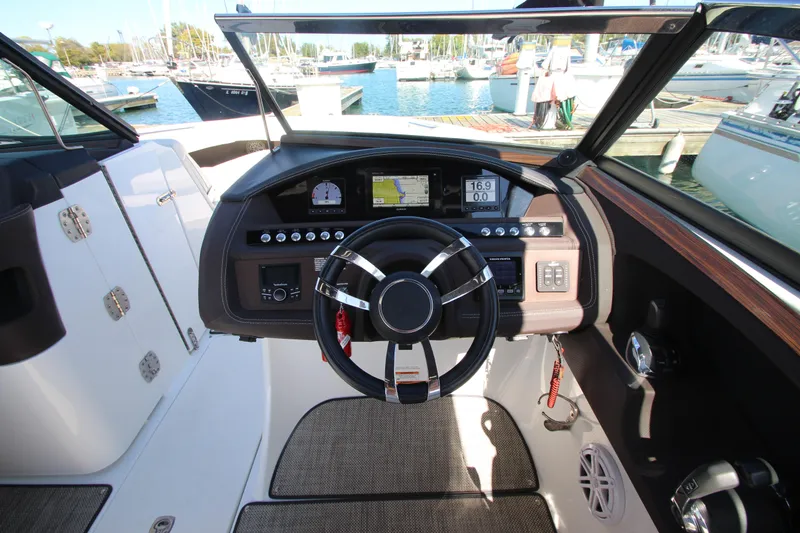Slide: The Image of 2016 Cobalt R30 boat dashboard with steering wheel, controls, and navigation display at marina. - 48