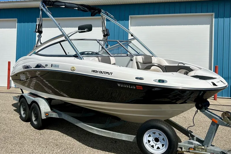 Slide: The Image of 2008 Yamaha 212X boat on trailer, high output model, parked outside blue building. - 2