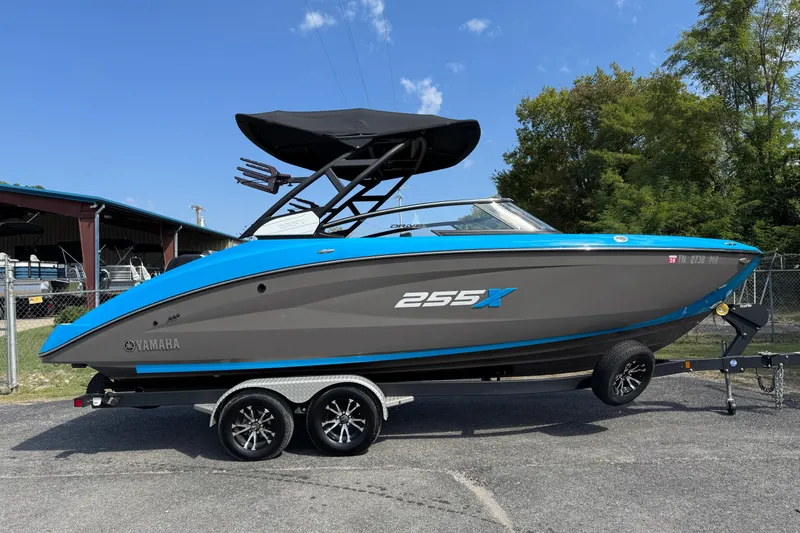 Slide: The Image of 2022 Yamaha Boats 255XD, blue and gray, on a trailer, outdoors. - 2
