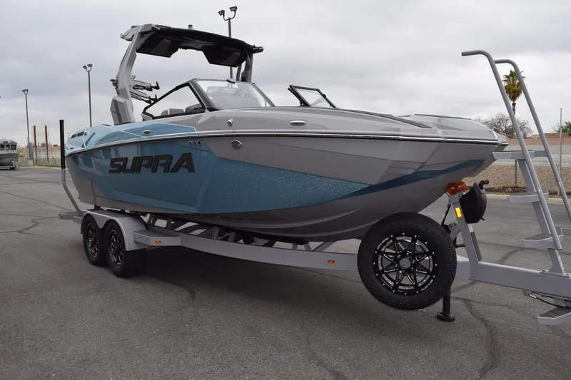Slide: The Image of 2025 Supra SA boat on trailer, sleek design, gray and blue color scheme. - 2