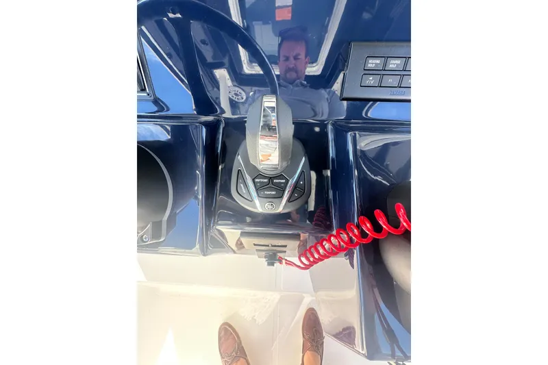 Slide: The Image of 2024 Pursuit S 288 Sport boat dashboard with controls and red coiled cord. - 12