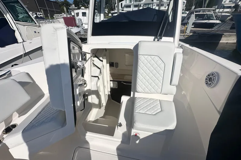 Slide: The Image of 2024 Pursuit S 288 Sport boat interior with white seating and storage access. - 18
