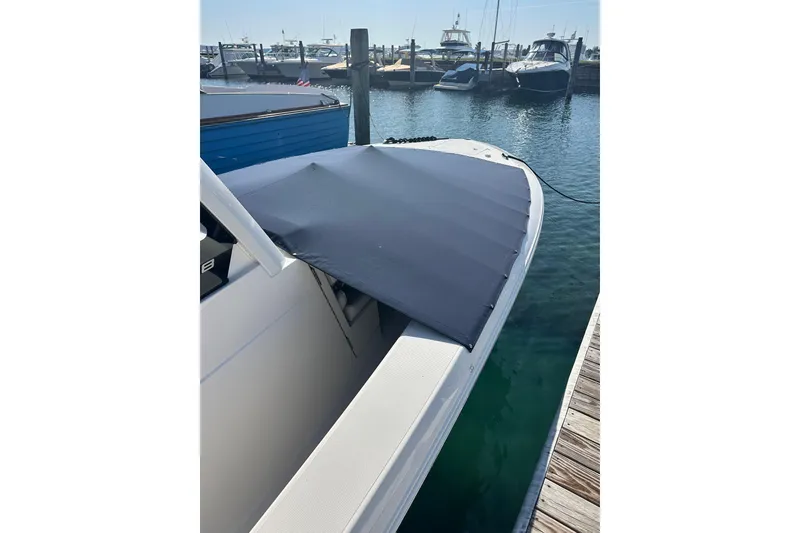 Slide: The Image of 2024 Pursuit S 288 Sport boat docked with a protective cover, surrounded by water and other boats. - 5