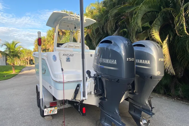 Slide: The Image of 2020 Robalo Center Console boat with twin Yamaha 150 engines, parked near palm trees. - 25