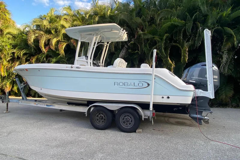 Slide: The Image of 2020 Robalo Center Console boat on trailer, parked near lush greenery. - 6