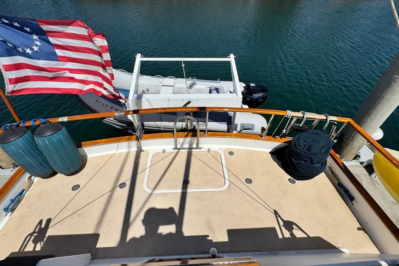 Slide: The Image of 1980 Californian Tri-Cabin Trawler deck with American flag and dinghy on water. - 10