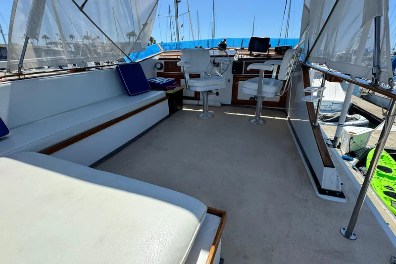 Slide: The Image of 1980 Californian Tri-Cabin Trawler interior with seating and helm, docked at marina. - 12