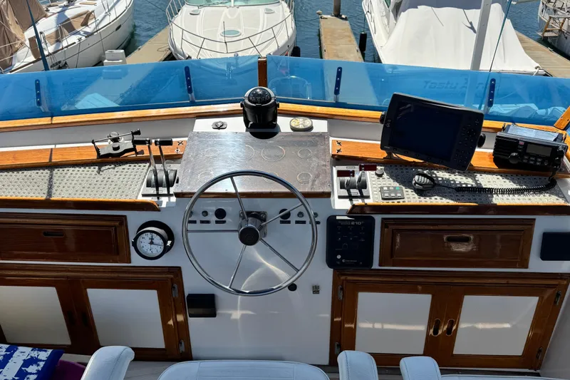 Slide: The Image of 1980 Californian Tri-Cabin Trawler helm with steering wheel, navigation equipment, and wooden accents. - 15