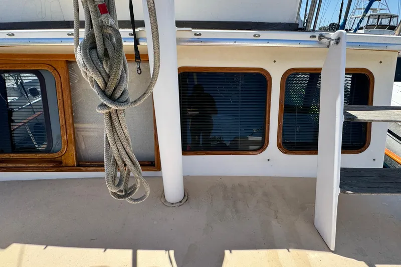 Slide: The Image of 1980 Californian Tri-Cabin Trawler deck with coiled rope and wooden-framed windows. - 21