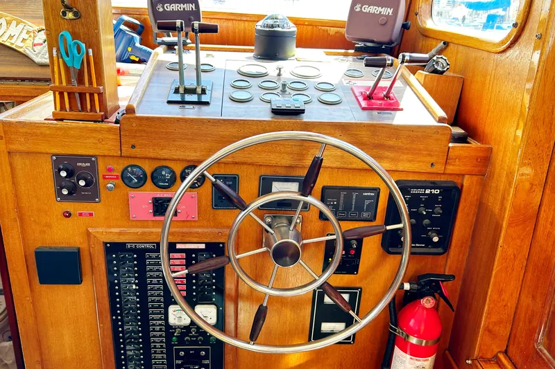 Slide: The Image of 1980 Californian 42 LRC boat helm with steering wheel, navigation controls, and fire extinguisher. - 48