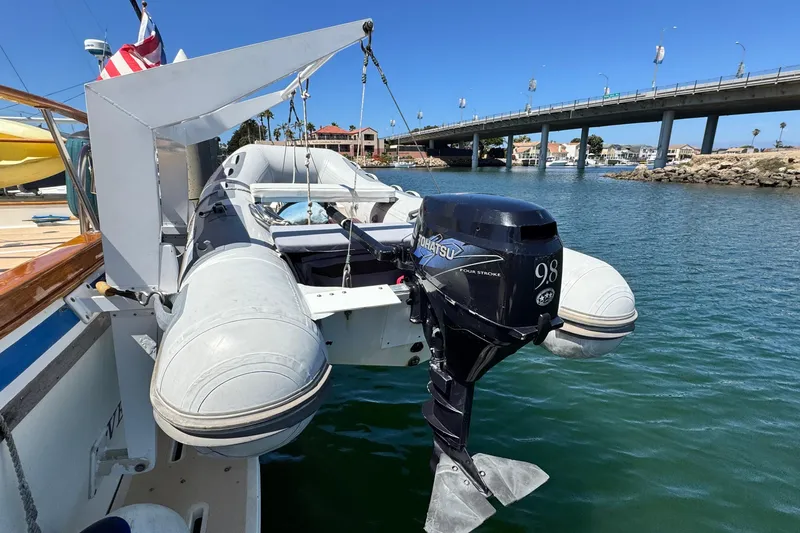 Slide: The Image of 1980 Californian Tri-Cabin Trawler with inflatable dinghy and outboard motor, docked near a bridge. - 6