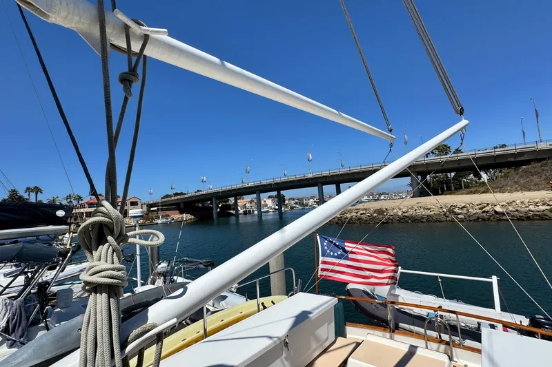 Slide: The Image of 1980 Californian Tri-Cabin Trawler docked near a bridge, featuring nautical ropes and American flag. - 9