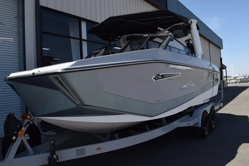 Slide: The Image of 2025 Nautique Super Air Nautique G23 Paragon boat on trailer outside warehouse. - 2