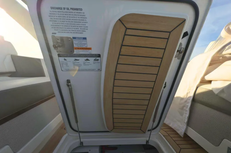 Slide: The Image of 2022 Tiara Yachts 34 LS interior hatch with safety warnings and wooden detailing. - 23