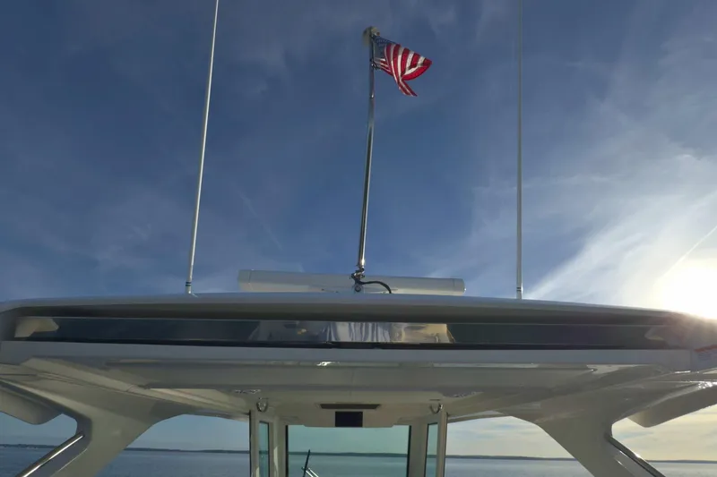 Slide: The Image of 2022 Tiara Yachts 34 LS with American flag against clear sky. - 24
