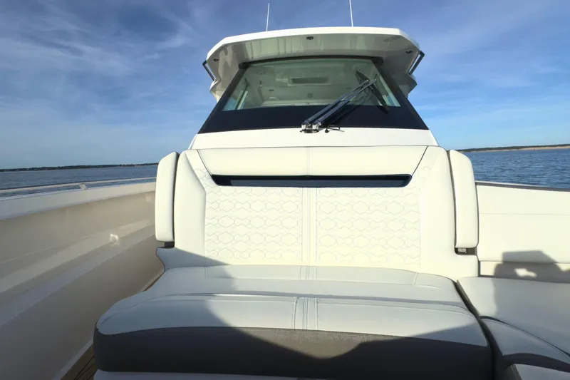 Slide: The Image of 2022 Tiara Yachts 34 LS boat interior with white seating and windshield, on calm water. - 50