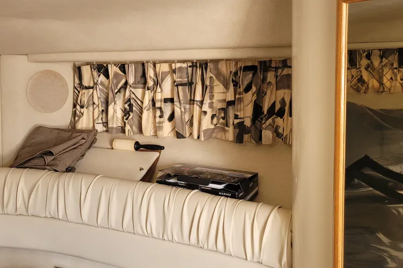 Slide: The Image of Interior of 1997 Sea Ray 330 Express Cruiser with patterned curtains and cushioned seating. - 37