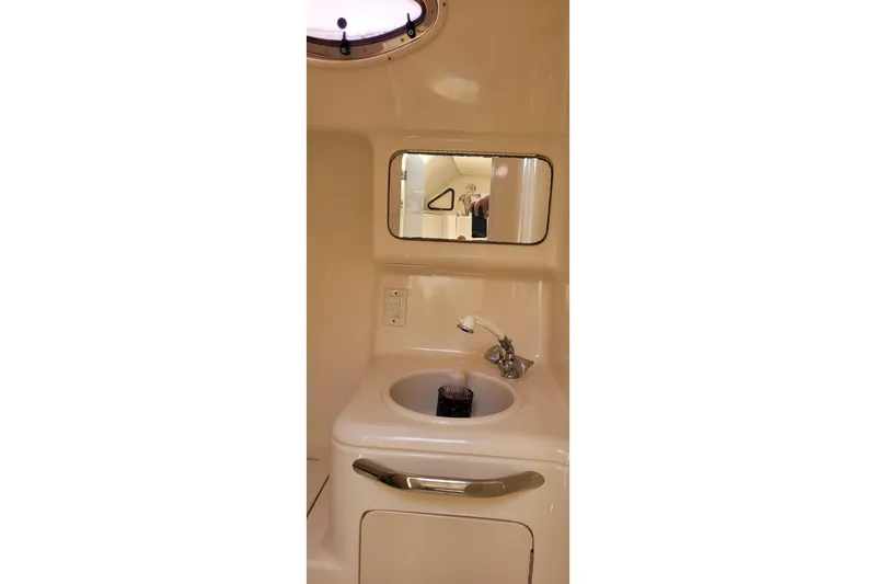 Slide: The Image of 1997 Sea Ray 330 Express Cruiser bathroom with sink, mirror, and porthole window. - 38