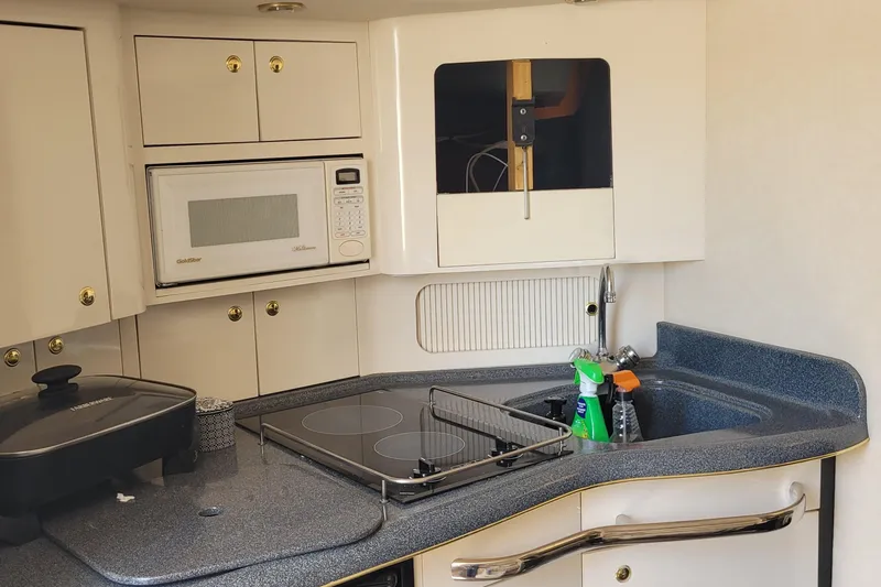 Slide: The Image of 1997 Sea Ray 330 Express Cruiser kitchen with microwave, stove, and sink. - 40