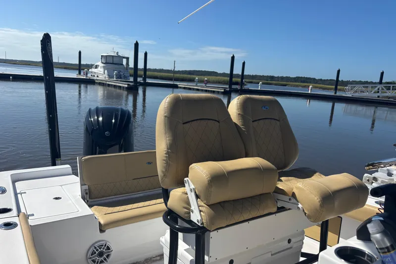 Slide: The Image of 2021 Sportsman Masters 247 Bay Boat interior with tan seating at a marina. - 11