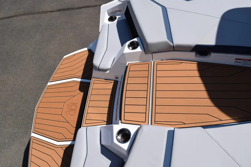 Slide: The Image of 2025 Nautique Super Air Nautique S23 boat deck with teak-style flooring and cushioned seating. - 14