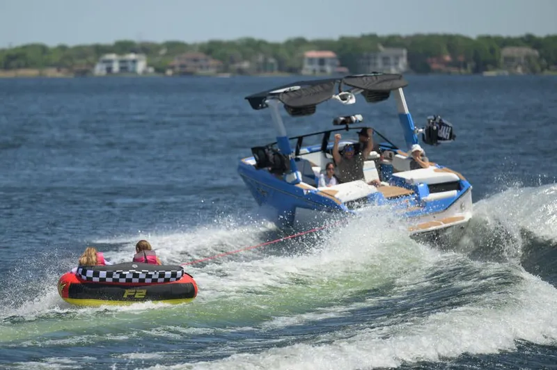 Slide: The Image of Manufacturer Provided Image: 2025 Nautique Super Air Nautique S23 towing a tube on a sunny lake. - 19