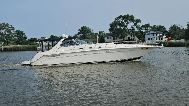 Slide: The Image of 1999 Sea Ray 500 Sundancer yacht cruising on a calm river near residential area. - 1