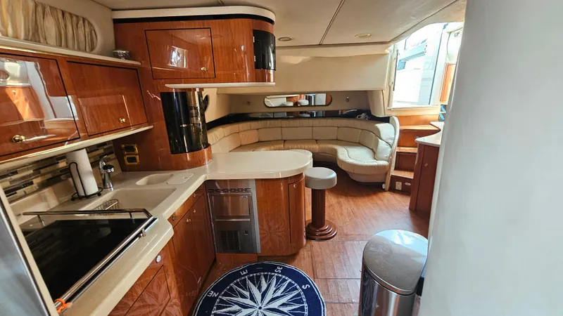 Slide: The Image of 1999 Sea Ray 500 Sundancer interior with kitchen and seating area, featuring wood cabinetry. - 38