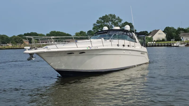 Slide: The Image of 1999 Sea Ray 500 Sundancer yacht on calm water near residential area. - 4