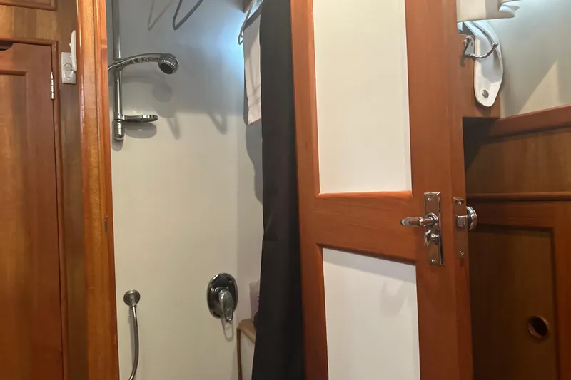 Slide: The Image of Shower area inside 2000 Island Gypsy 36 boat, featuring wooden door and chrome fixtures. - 14