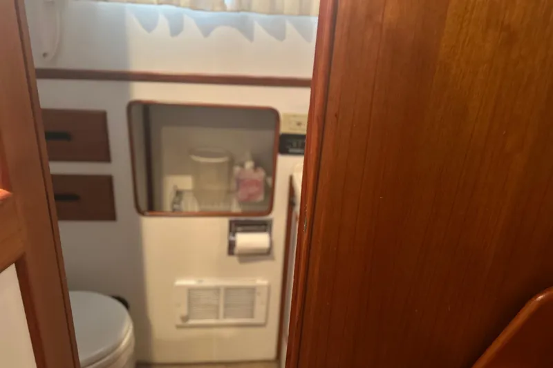 Slide: The Image of Bathroom interior of a 2000 Island Gypsy 36 boat with wooden accents. - 15