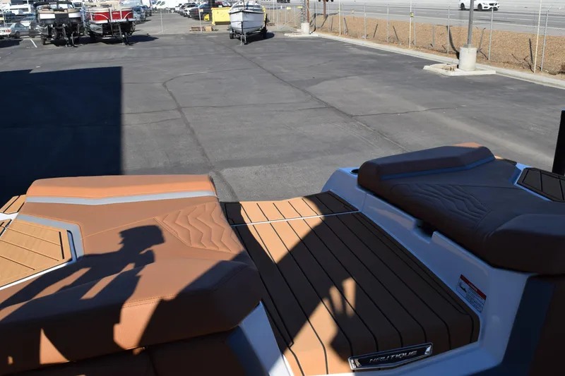 Slide: The Image of 2025 Nautique Super Air Nautique G23 Paragon boat with tan seating in a parking lot. - 16
