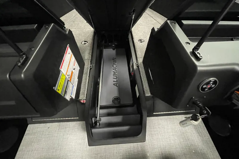 Slide: The Image of 2026 Alumacraft Competitor 175X Sport interior storage compartment with safety labels and controls. - 9