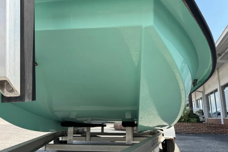 Slide: The Image of 2025 Mowdy 16 Cat boat hull on trailer, showcasing sleek design and mint green color. - 11