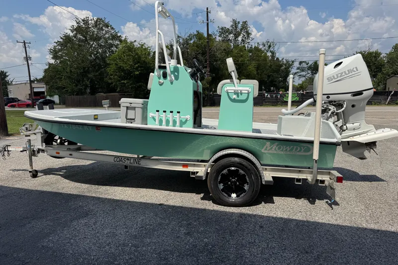 Slide: The Image of 2025 Mowdy 16 Cat boat on trailer with Suzuki outboard motor, parked outdoors. - 3