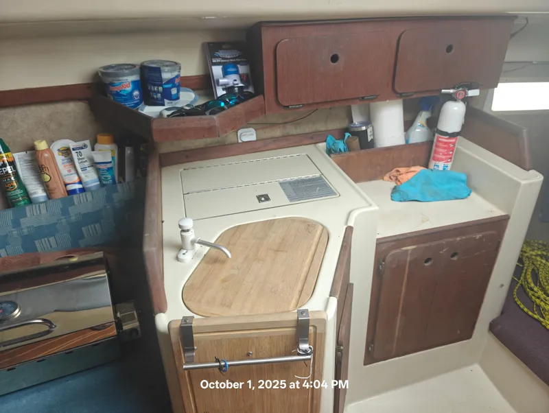 Slide: The Image of Interior of a 1990 Hunter 27-2 sailboat kitchen with storage and cleaning supplies. - 16
