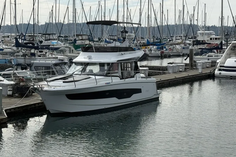 Slide: The Image of 2025 Jeanneau NC 1095 Fly yacht docked in a marina, surrounded by sailboats. - 18