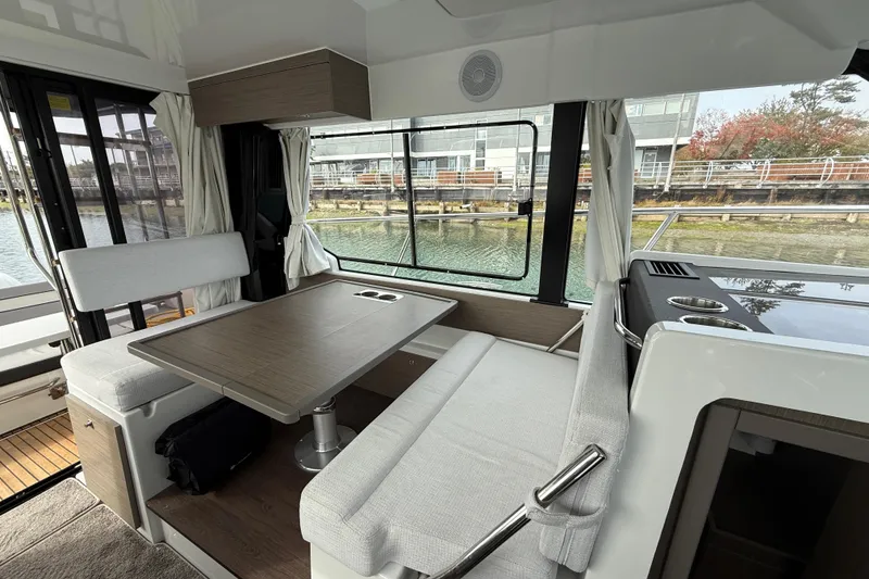 Slide: The Image of Interior of 2025 Jeanneau NC 1095 Fly, featuring a cozy dining area with waterfront view. - 26
