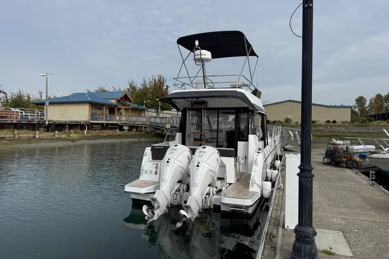 Slide: The Image of 2025 Jeanneau NC 1095 Fly yacht docked at marina with twin outboard engines. - 39