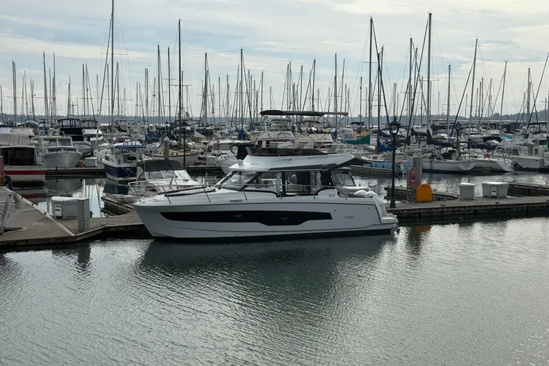 Slide: The Image of 2025 Jeanneau NC 1095 Fly yacht docked in a marina with sailboats. - 40