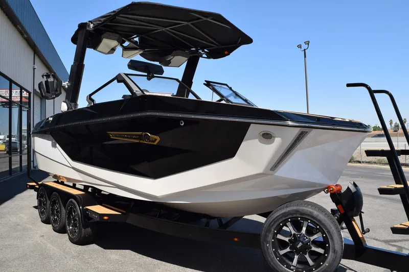 Slide: The Image of 2025 Nautique Super Air Nautique G23 boat on trailer, black and white design. - 1
