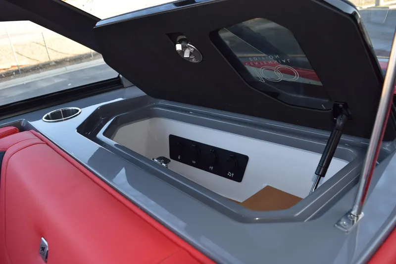Slide: The Image of 2025 Nautique Super Air Nautique G23 storage compartment with red seating and cup holder. - 12