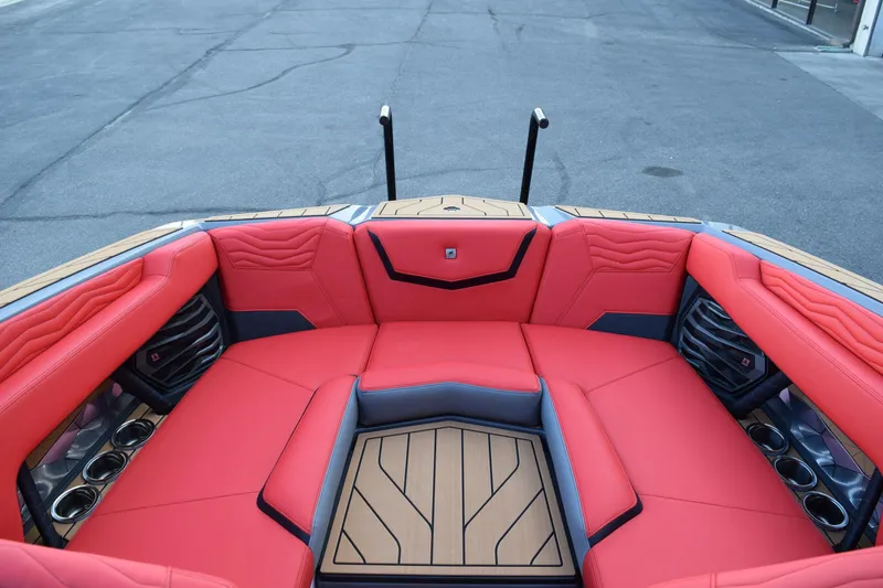 Slide: The Image of 2025 Nautique Super Air Nautique G23 boat interior with red seating and cup holders. - 15